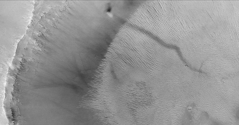 Een wervelstormpje (dust devil) kruipt op Mars tegen een kraterwand omhoog