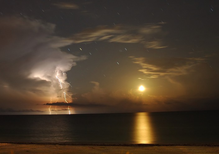 The alluring digital image is a time exposure, by chance capturing the details of a brief flash of lightning along with an overexposed Moon and dramatic cloud formations. In fact, the exposure is long enough to show the background stars as short streaks or trails. The bright yellowish star trail, just above and right of the lightning flash, is red giant star Antares.