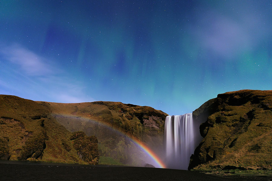 Cascada, arco de Luna y aurora en Islandia